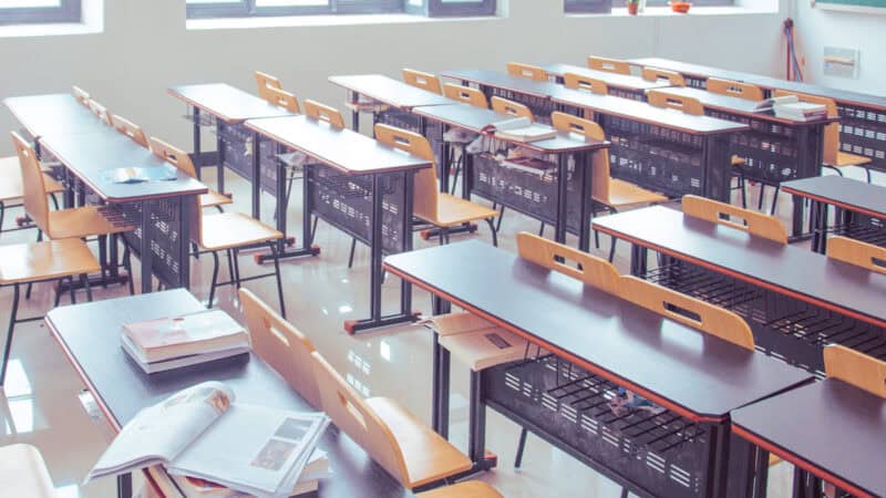 Concurso Votorantim 2026: sala de aula vazia com carteiras e livros, imagem ilustrativa sem logomarca